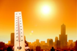 heat wave in the city and hand showing thermometer for high temperature